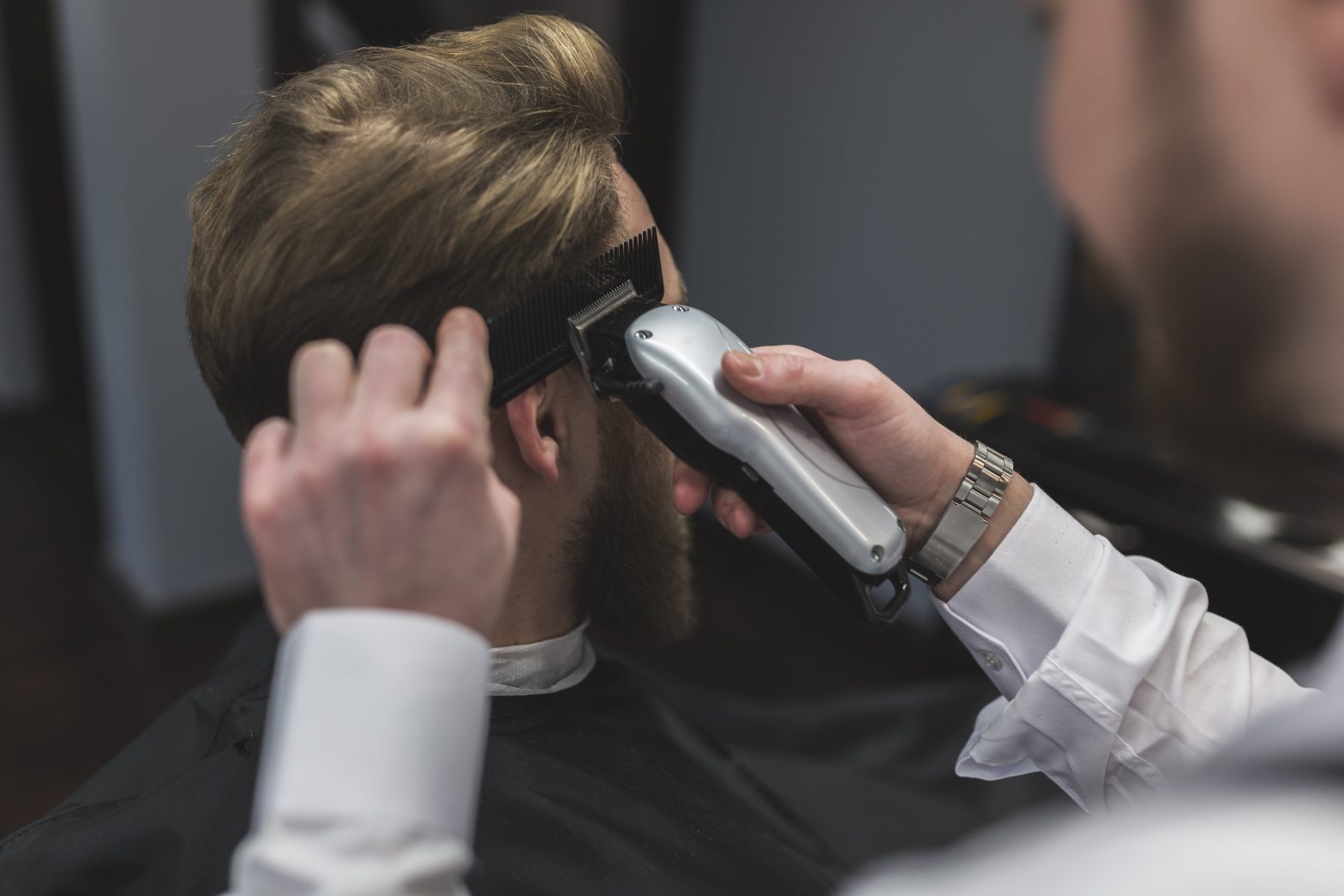 A barber making top hairstyle of the men.