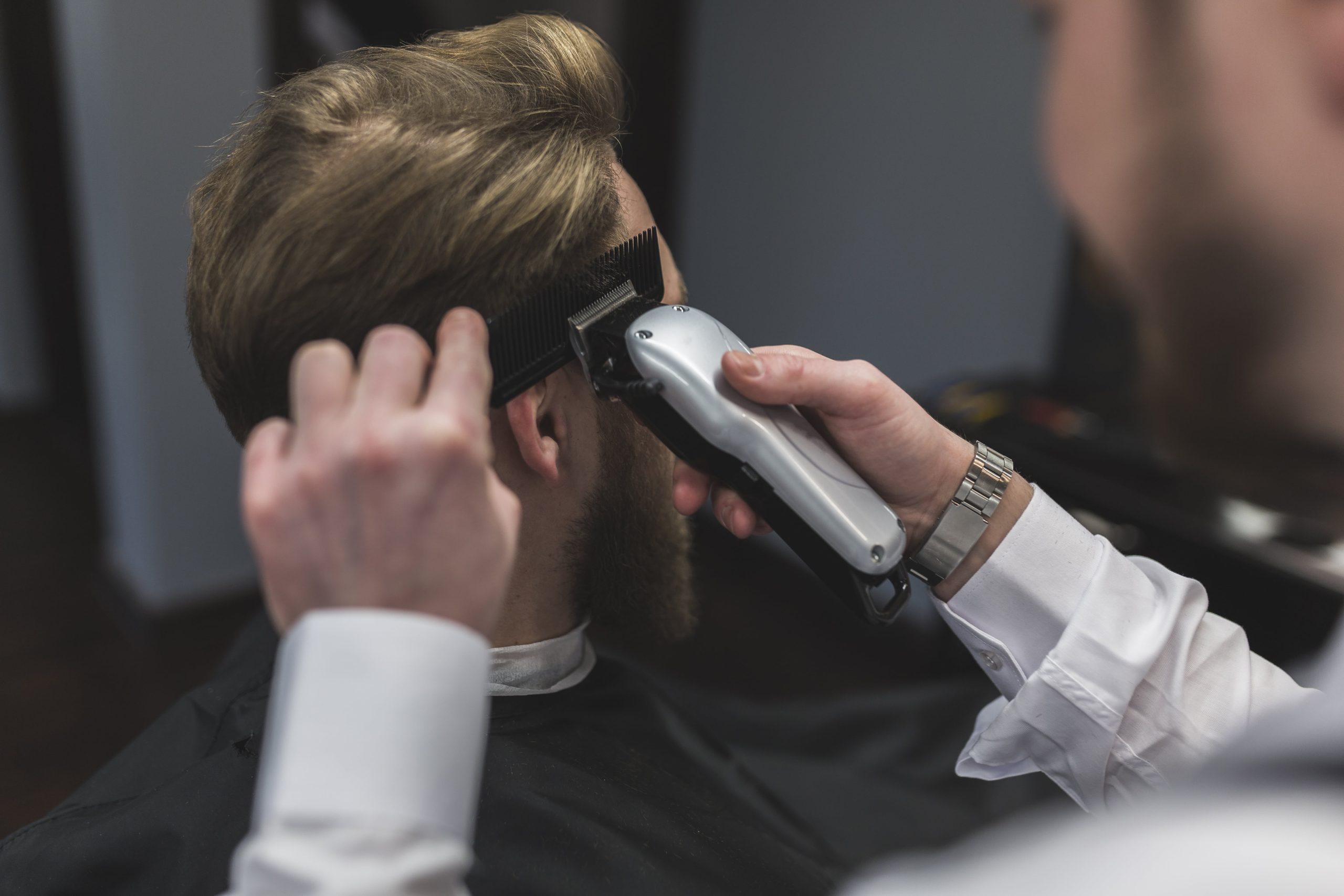 A barber making top hairstyle of the men.